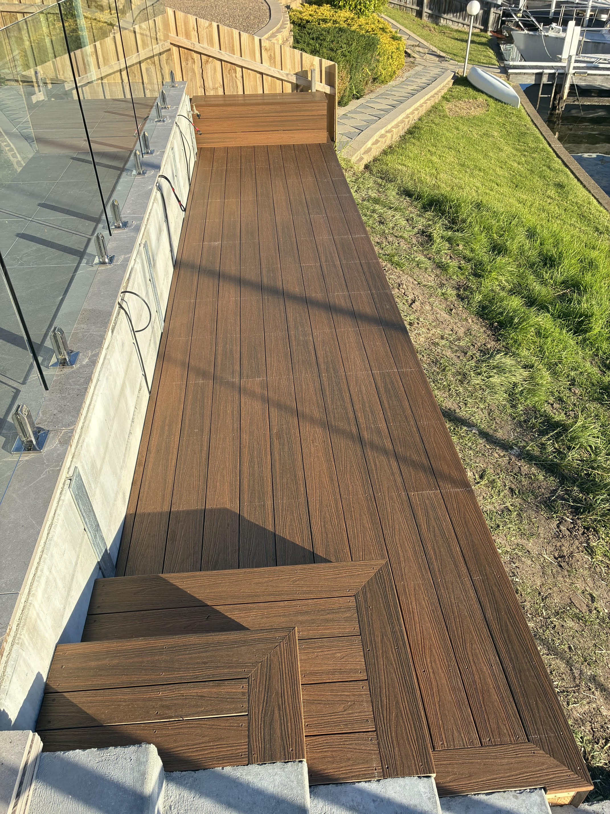 Waterfront composite deck with frameless glass balustrade in Paynesville by NPD Building Solutions